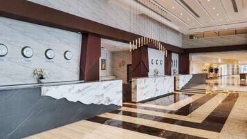 A hotel reception area with marble counters, clocks indicating different cities, and a modern design.