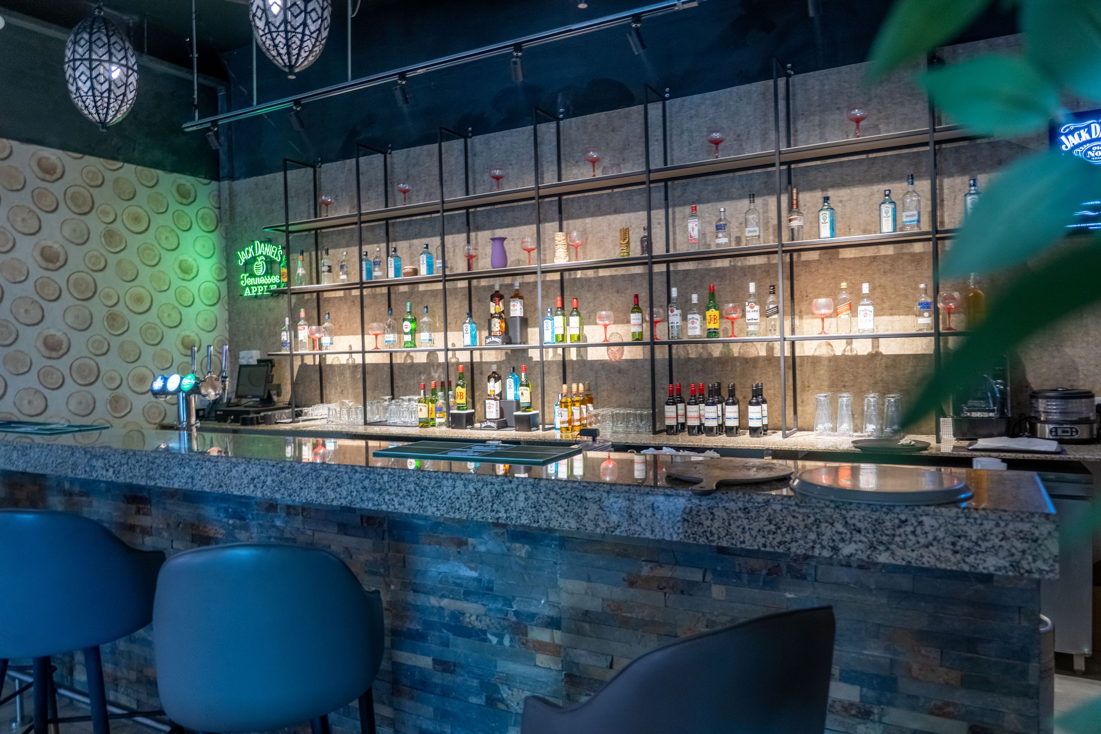 Uma área de bar com balcão, banquetes e diversos frascos e copos.