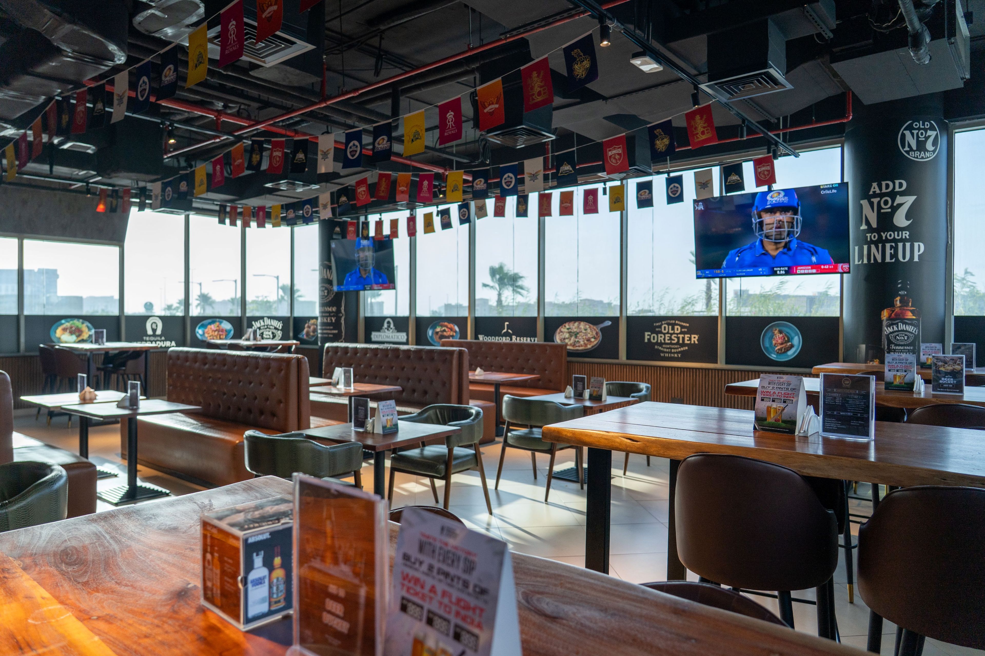 A restaurant with booths, tables, and a TV screen.