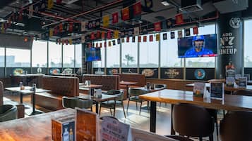 A restaurant with booths, tables, and a TV screen.