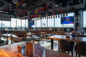 A restaurant with booths, tables, and a TV screen. - Vogo Grand Hotel (Dubai)