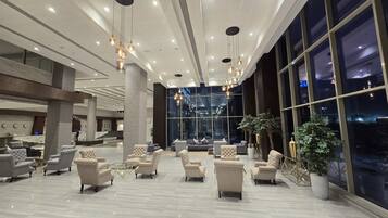 A spacious lobby with modern furniture, large windows, and hanging pendant lights.