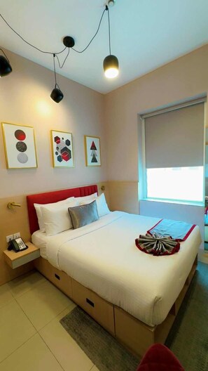 A hotel room with a bed, bedside table, and a window. - Vogo Grand Hotel (Dubai)