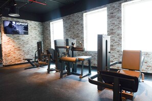 A gym with exercise equipment, a television displaying 'HIPHOP,' and large windows. - Vogo Grand Hotel (Dubai)