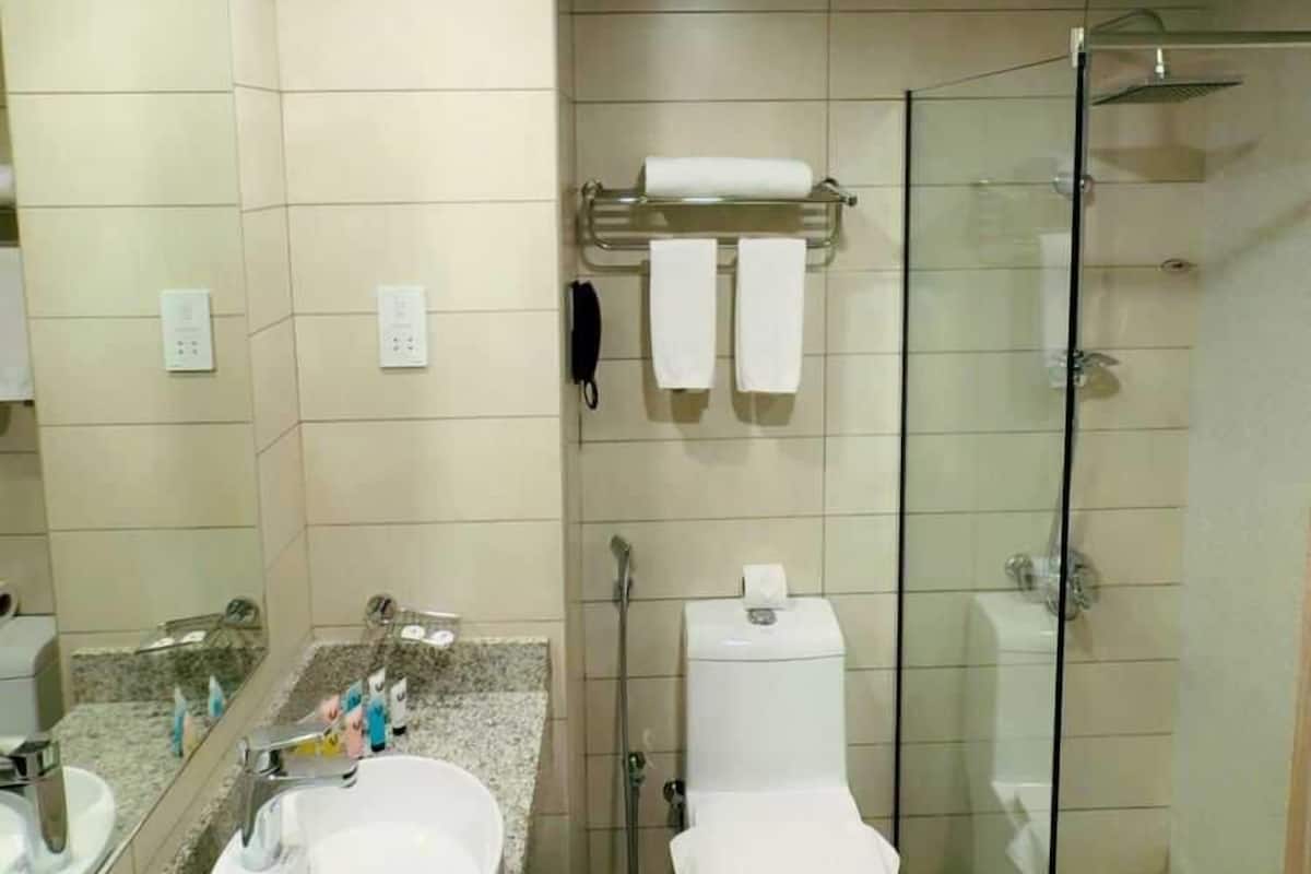 Un baño moderno con lavamanos de granito, cabina de ducha de vidrio y un inodoro con toallero.