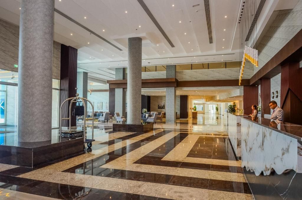 A spacious lobby with a marble floor, large columns, a reception desk, and a view into the hotel rooms.