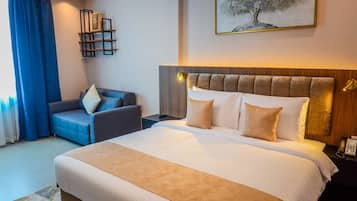 Een hotelkamer met een groot bed, een bank, een bureau en een schilderij aan de muur.