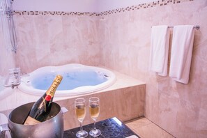 A bathroom with a jacuzzi, a champagne bottle, and two glasses of champagne. - Arenal Manoa Resort And Hot Springs (La Fortuna)