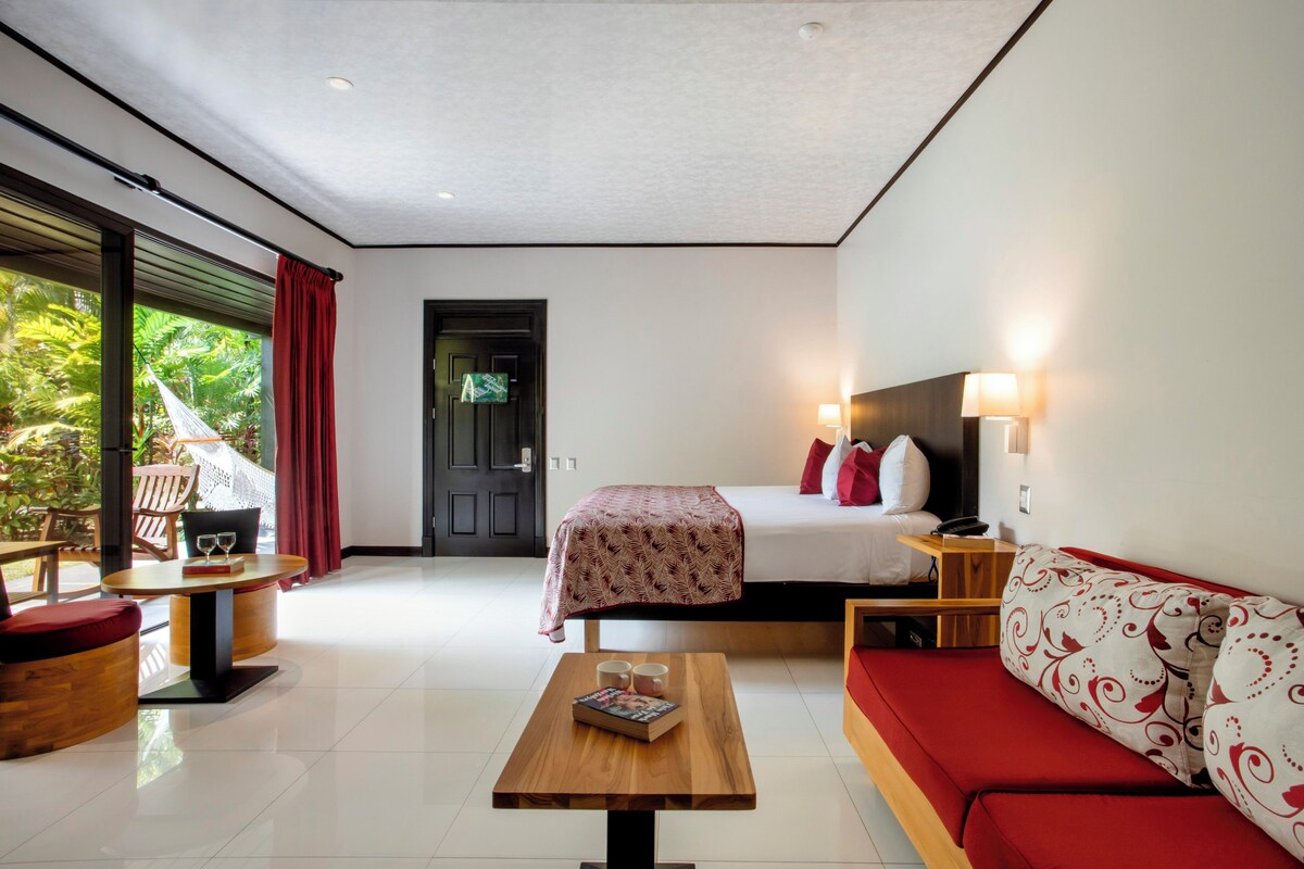 A hotel room with a bed, a sofa, a table, and a view of the outdoors.