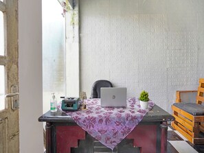 A room with a laptop on a table, a small plant, a chair, and a wooden bench. - Spot On 91672 House Of Henny Tea (Jember)