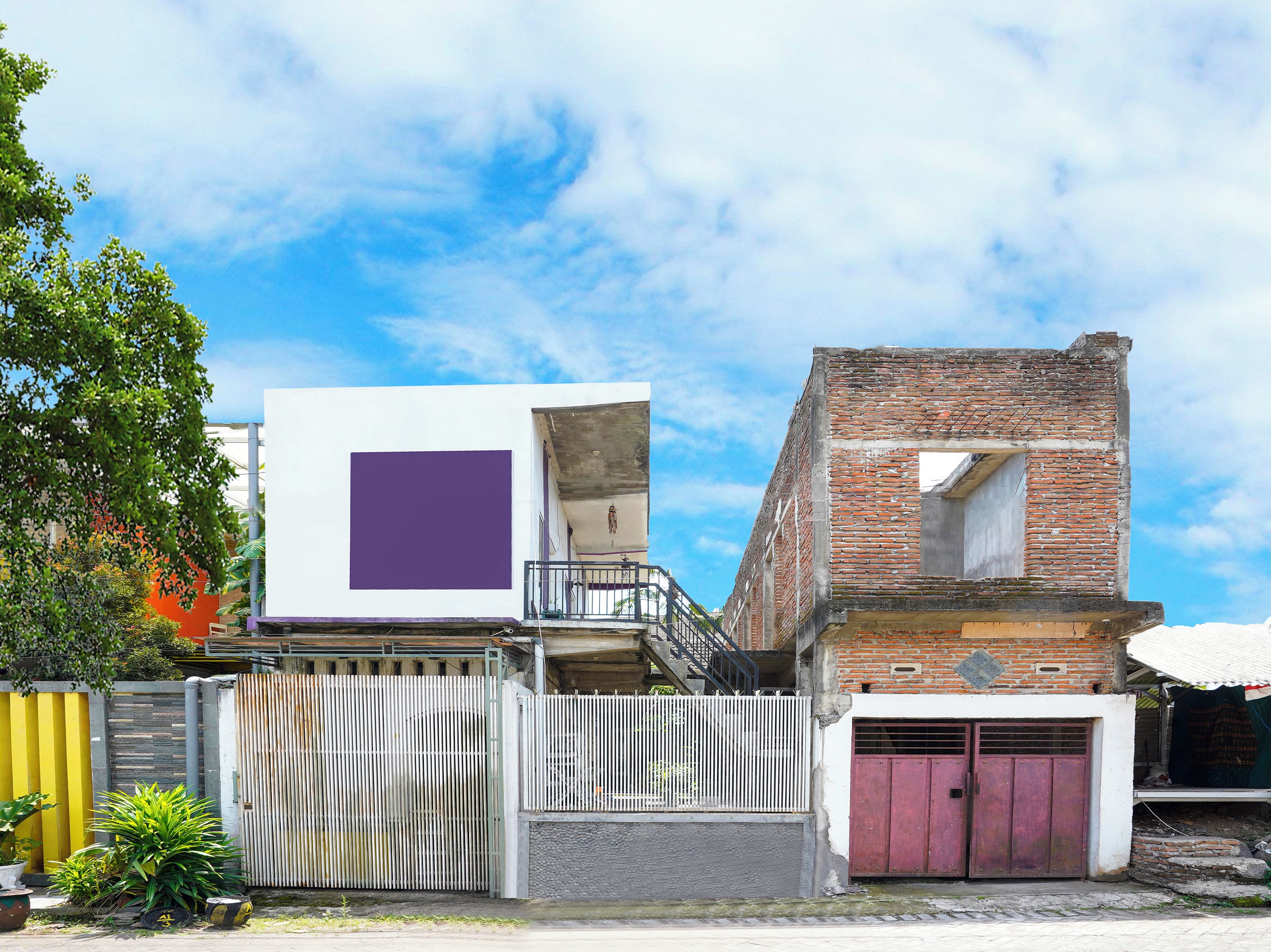 A two-story building with a white and purple facade, a brick section, and a gated entrance.