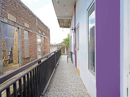 Un pasillo estrecho con un balcón, una pared de ladrillo y una ventana.