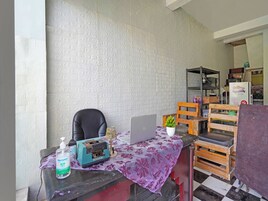 Una habitación con pared de ladrillo, una laptop sobre una mesa, una silla, una planta pequeña y un banco de madera.