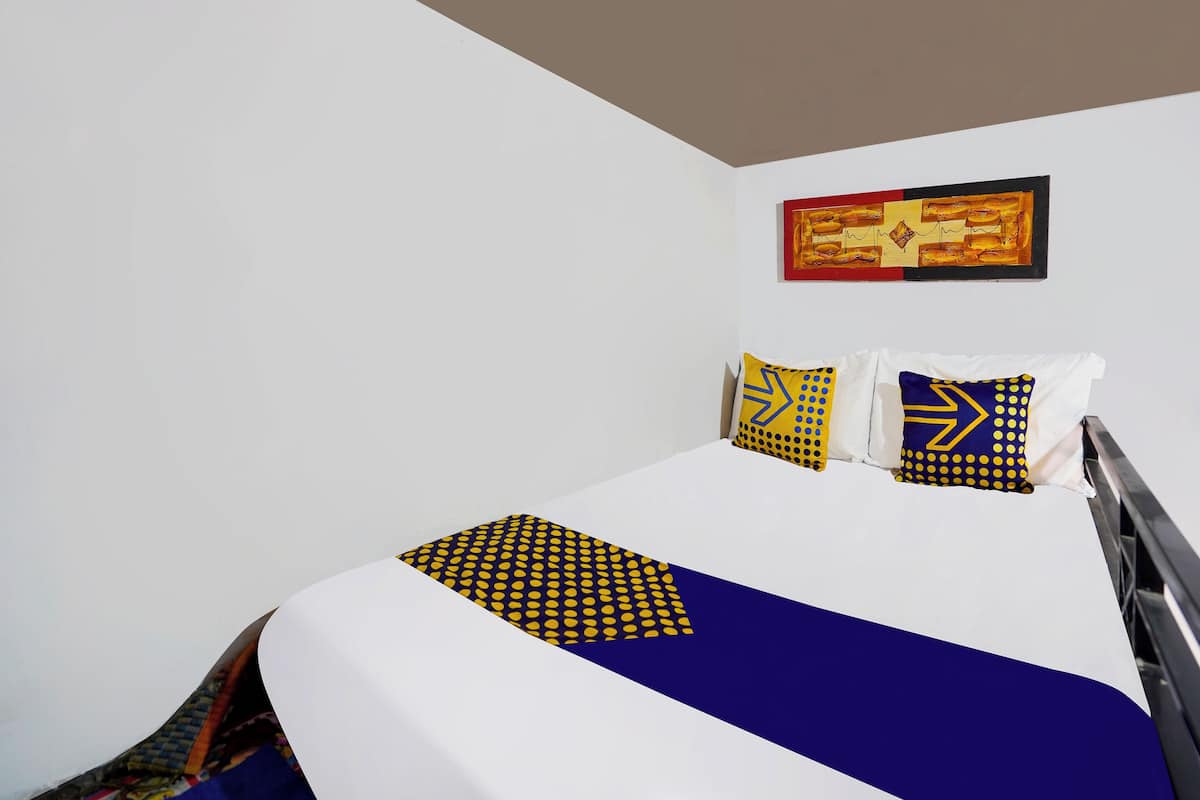 Ein Hotelzimmer mit einem Bett, weißen Wänden und einem Bild über dem Bett.