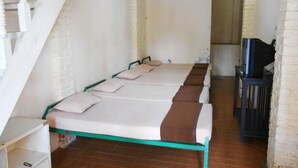 A room with a long bed, a TV, and a staircase.