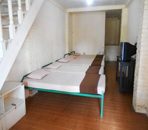 A room with a long bed, a TV, and a staircase.