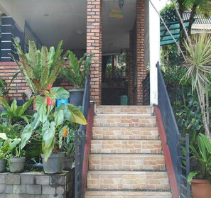 A staircase leading to a building entrance with brick walls and potted plants. - Cunang Hill Hotel & Resort by Zuzu (Cilobak)