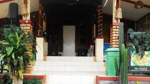 A building entrance with steps leading up to a door, surrounded by plants and a sign for 'd Cunang Caffe & Resto'. - Cunang Hill Hotel & Resort by Zuzu (Cilobak)