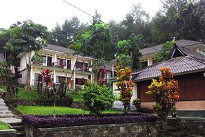 A traditional building with multiple rooms, a stone pathway, and lush greenery.