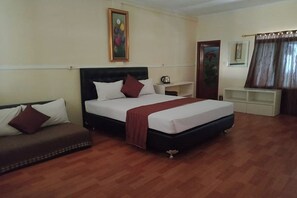 A hotel room with a bed, a sofa, a painting on the wall, a coffee table, and a window with curtains.