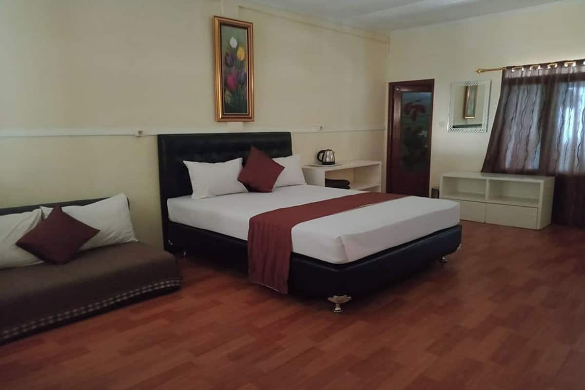 Ein Hotelzimmer mit Bett, Sofa, einem Bild an der Wand, Couchtisch und einem Fenster mit Vorhängen.