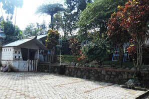 A paved courtyard with a stone wall, a small building labeled 'Angel,' and lush greenery. - Cunang Hill Hotel & Resort by Zuzu (Cilobak)