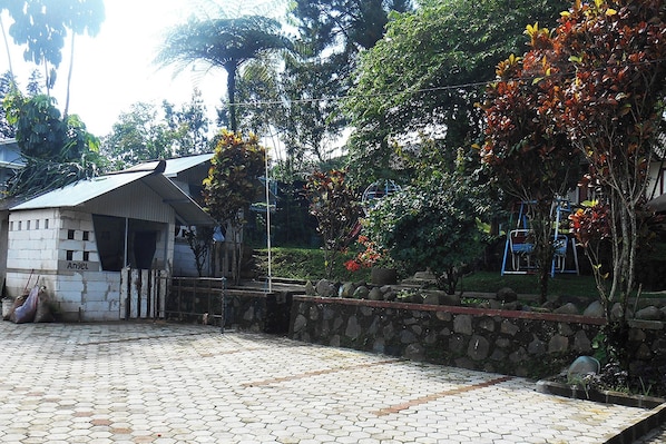 A paved courtyard with a stone wall, a small building labeled 'Angel,' and lush greenery.