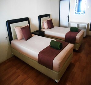 Two single beds with headboards, a nightstand, and a small table with a lamp.