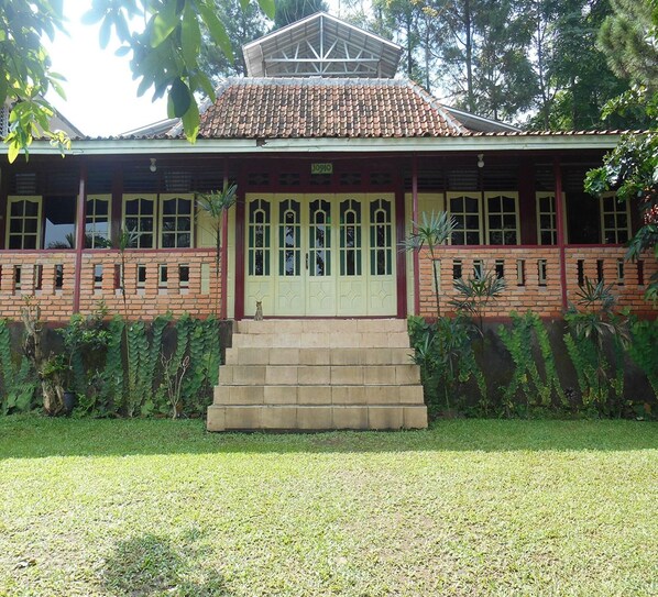 A building with a tiled roof, a front porch, and a staircase leading to the entrance.