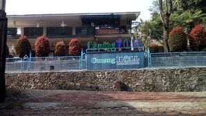 A sign for Cumming Hotel and Resort with a stone wall and a paved area in front.