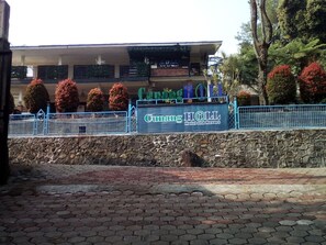 A sign for Cumming Hotel and Resort with a stone wall and a paved area in front.