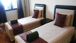 Two single beds with headboards, a nightstand, and a window with curtains.