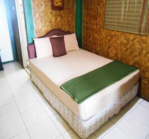 A bed with a green blanket, a wooden headboard, and a woven wall. - Cunang Hill Hotel & Resort by Zuzu (Cilobak)