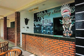 Una mesa de recepción con un cartel que dice 'Wulijing Sun Gungang HOLL Hotel and Resort', una máscara decorativa y un cartel que indica 'Oficina Principal'.