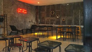 A café with tables and chairs arranged in a casual setting, a neon sign on the wall, and hexagonal wall decorations. - Cunang Hill Hotel & Resort by Zuzu (Cilobak)