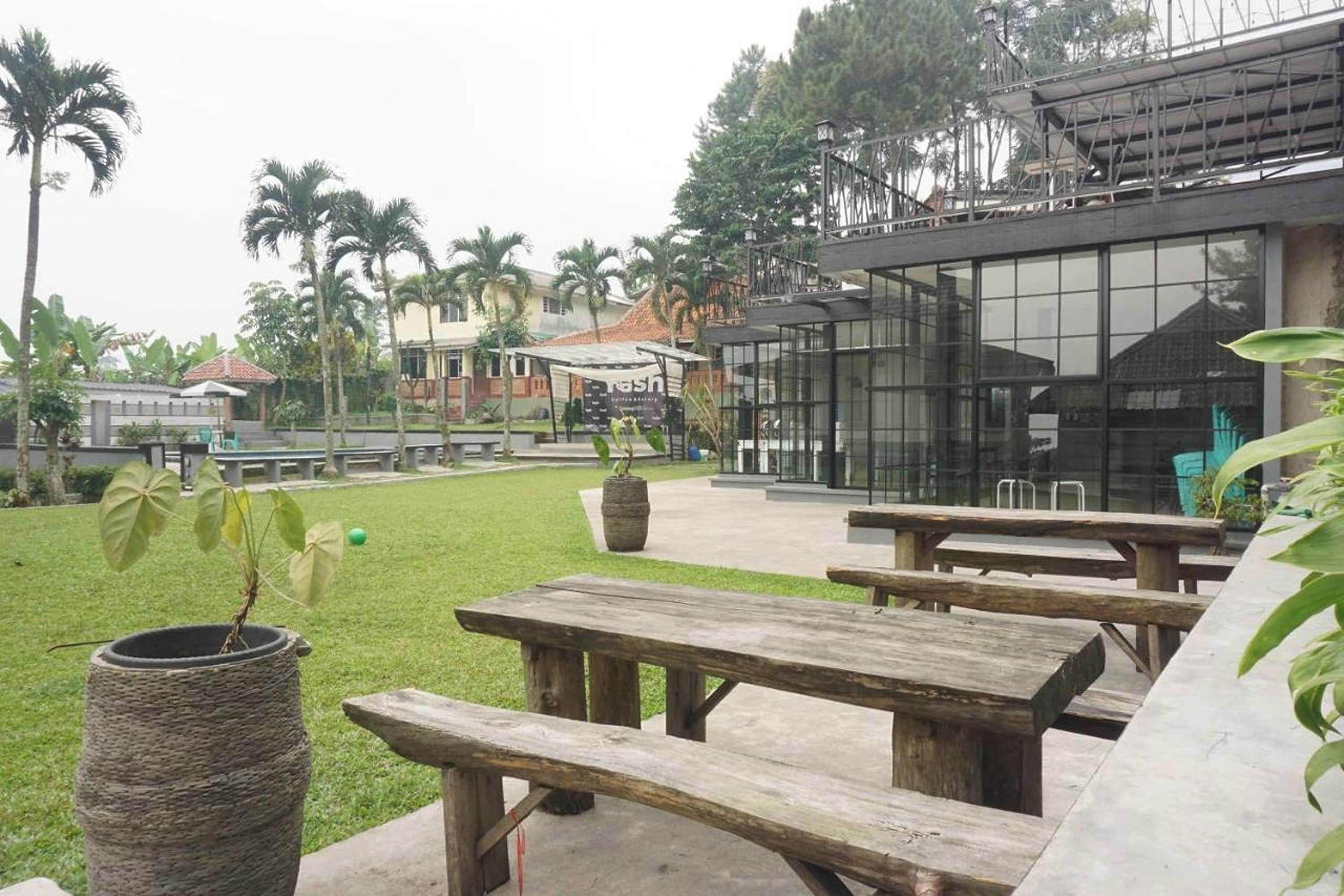 A courtyard with wooden picnic tables, a stone planter, and a modern building with large windows.