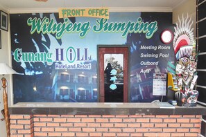 Ein Hotelrezeptionsschalter mit einem großen Schild für 'Wulijing Sunping Cunang HOLL Hotel and Resort', einem Konferenzraum, einem Schwimmbad und einem Außenbereich.