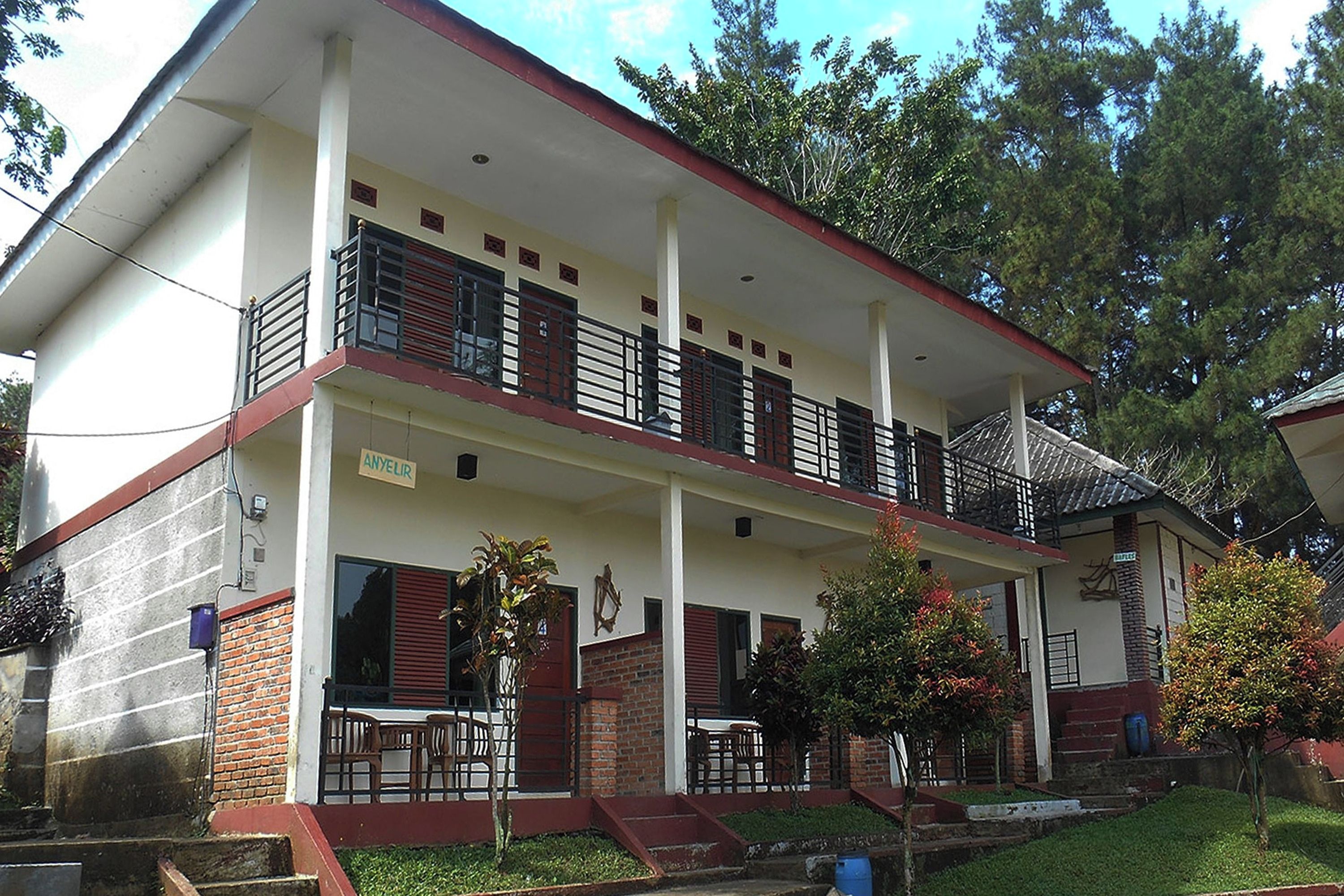 A two-story building with a balcony, a covered porch, and a brick lower level.