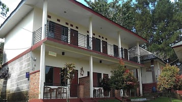 A two-story building with a balcony, a covered porch, and a brick lower level.
