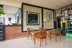 A restaurant interior with brick walls, wooden chairs, a tiled floor, and a green vending machine.