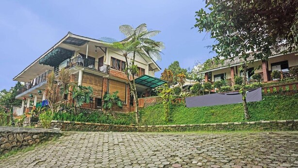 A two-story house with a balcony, surrounded by greenery and a cobblestone pathway. - Cunang Hill Hotel & Resort by Zuzu (Cilobak)