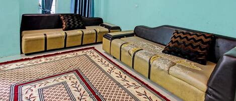 A living room with two sofas, a patterned rug, and a window with curtains.