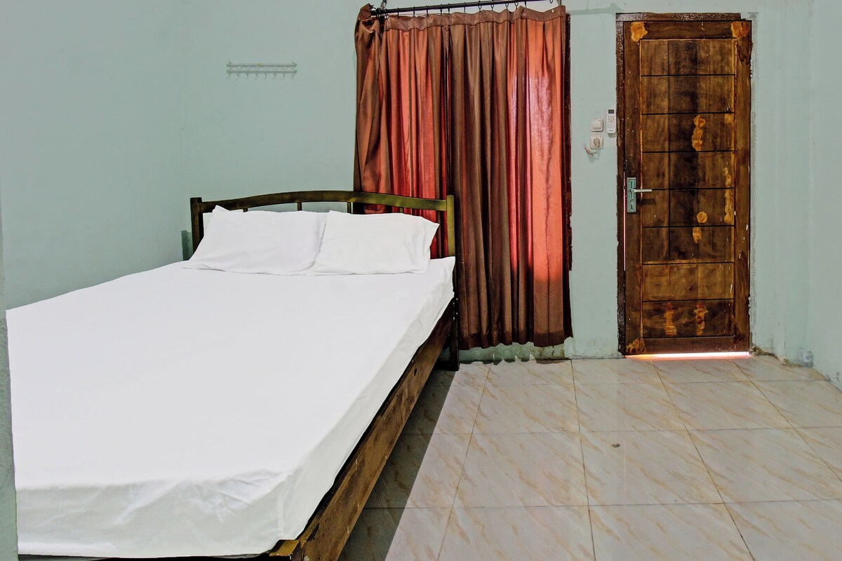 A bedroom with a single bed, a wooden door, and a curtain.