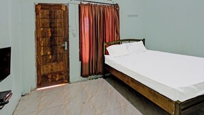 A room with a wooden door, a bed with white sheets, a red curtain, and an air conditioning unit on the wall. - Spot On 91771 Homestay Bang Haji (Praya)