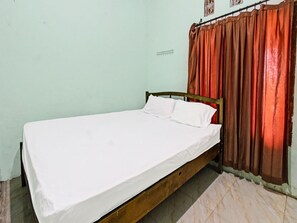 A single bed with a wooden frame and white bedding in a room with light green walls and a tiled floor. - Spot On 91771 Homestay Bang Haji (Praya)