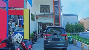 A building with a storefront, parked motorcycles, and a car. - Oyo 91432 Dalle 5151 Jeneponto (Tanjung Pinang)