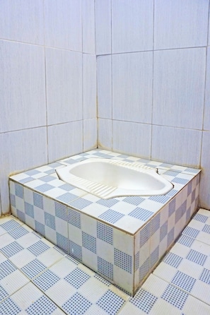 A bathroom with a white bathtub, tiled walls, and floor. - Oyo 91432 Dalle 5151 Jeneponto (Tanjung Pinang)