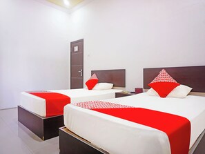 A hotel room with two beds, each with a red and white patterned bedspread, a wooden headboard, and a nightstand with a red box. - Oyo 91432 Dalle 5151 Jeneponto (Tanjung Pinang)