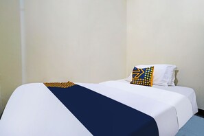 A single bed with a white and navy blue bedspread, a navy blue pillow with yellow geometric patterns, and a white pillow. - Spot On 91783 Urban Syariah Residence (Bandung)