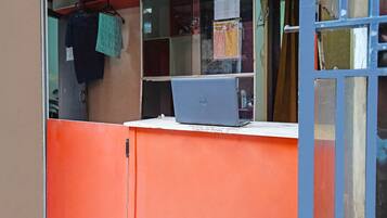 A laptop on a white counter with a red cabinet behind it.